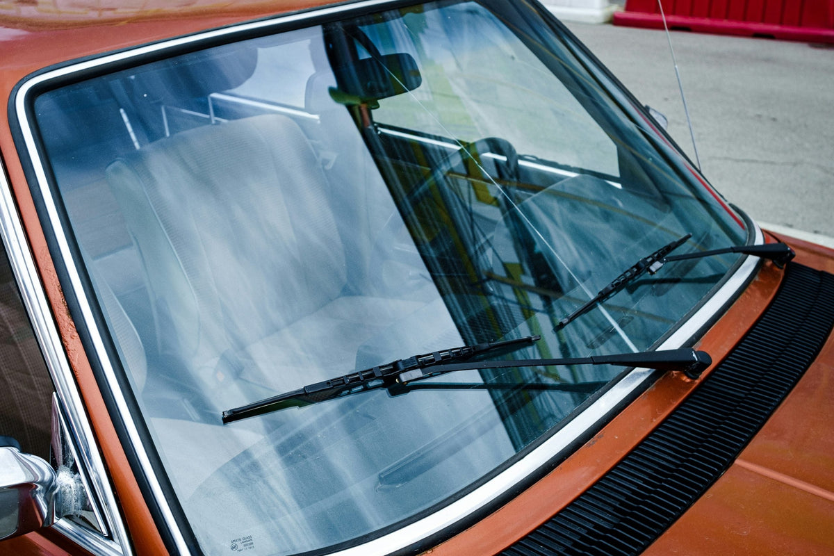 Windscreen wipers on an old, red car.